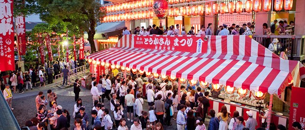 Люди на летнем фестивале в Японии у палаток с едой
